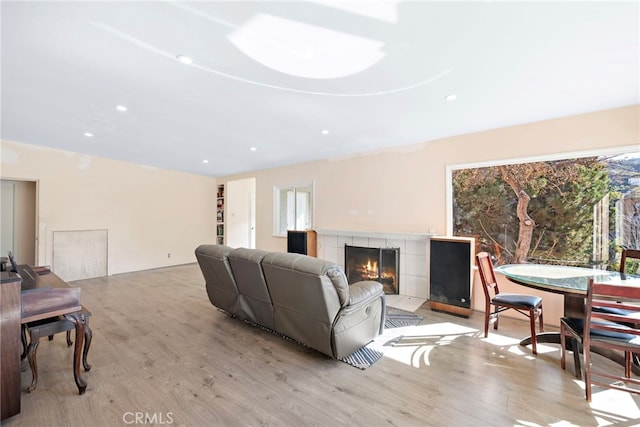 living room featuring a tiled fireplace and light hardwood / wood-style floors