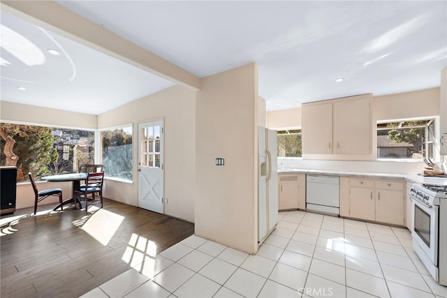 kitchen featuring light tile patterned flooring, white appliances, beam ceiling, cream cabinets, and backsplash