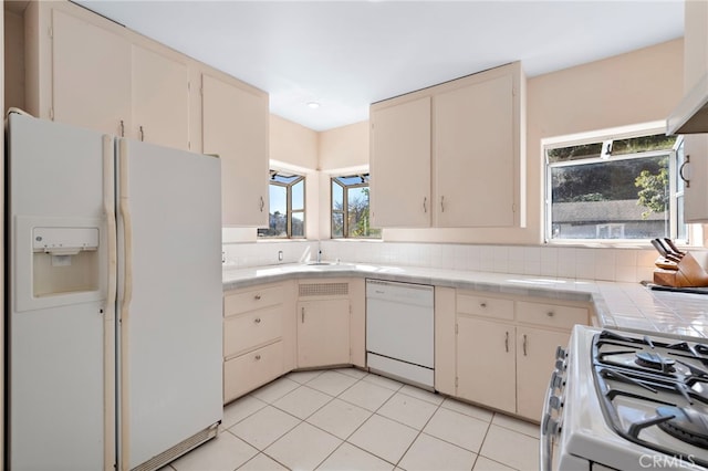 kitchen featuring tile countertops, sink, decorative backsplash, light tile patterned floors, and white appliances