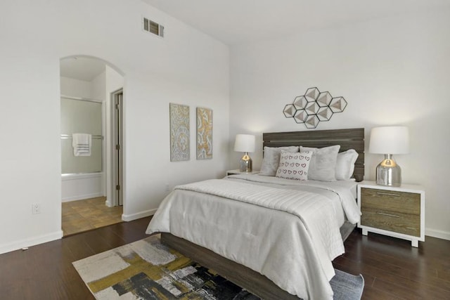 bedroom featuring ensuite bath and dark hardwood / wood-style floors