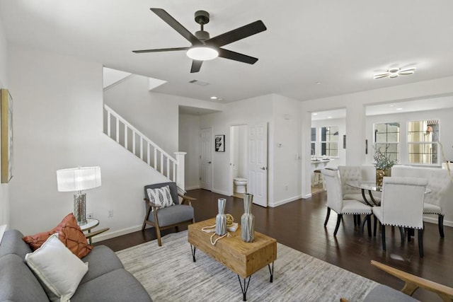 living room featuring dark wood-type flooring and ceiling fan