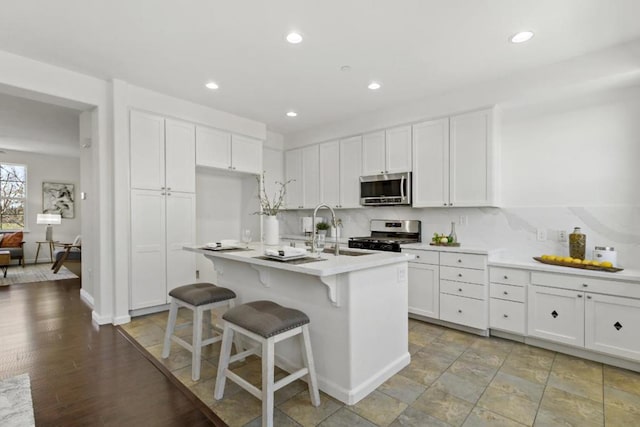 kitchen featuring white cabinetry, appliances with stainless steel finishes, a kitchen island with sink, and a breakfast bar area