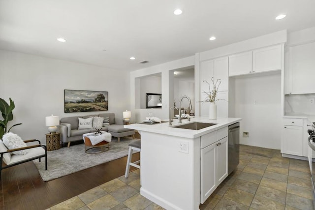 kitchen featuring a kitchen island with sink, sink, stainless steel dishwasher, and white cabinets