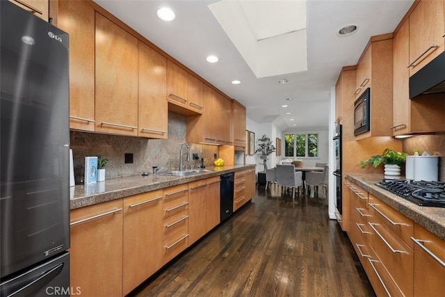 kitchen featuring sink, black appliances, a skylight, dark hardwood / wood-style flooring, and backsplash