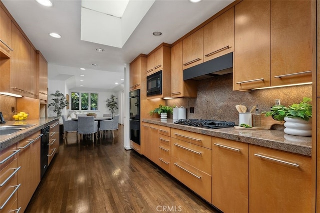 kitchen featuring ventilation hood, dark hardwood / wood-style floors, backsplash, and black appliances