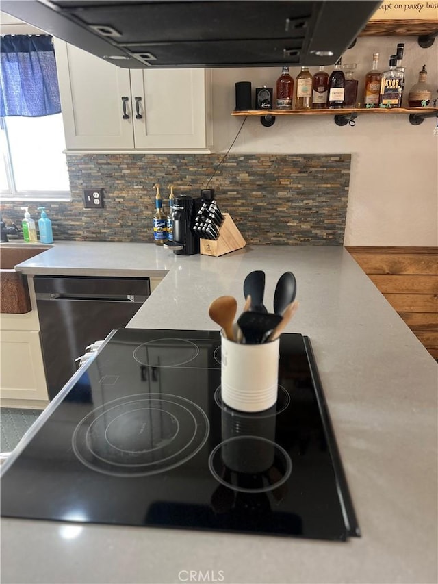 kitchen with white cabinetry, ventilation hood, black electric cooktop, decorative backsplash, and stainless steel dishwasher