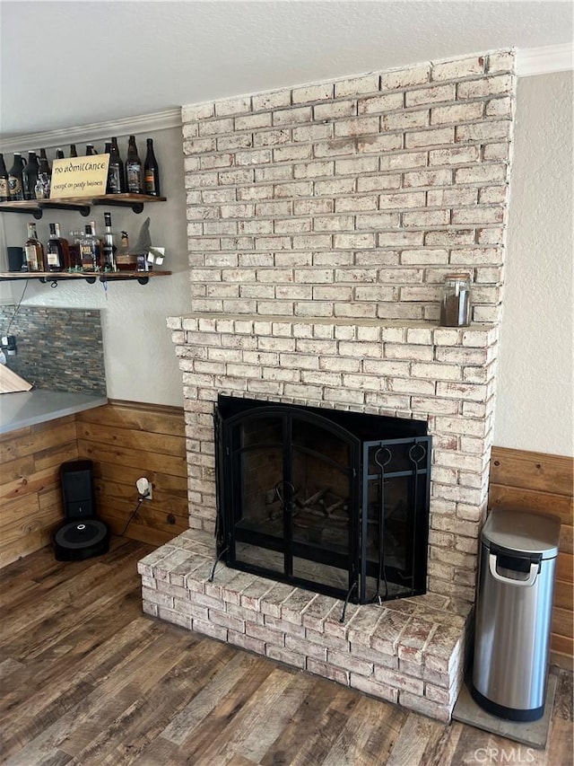 details featuring hardwood / wood-style floors, a fireplace, ornamental molding, and wood walls