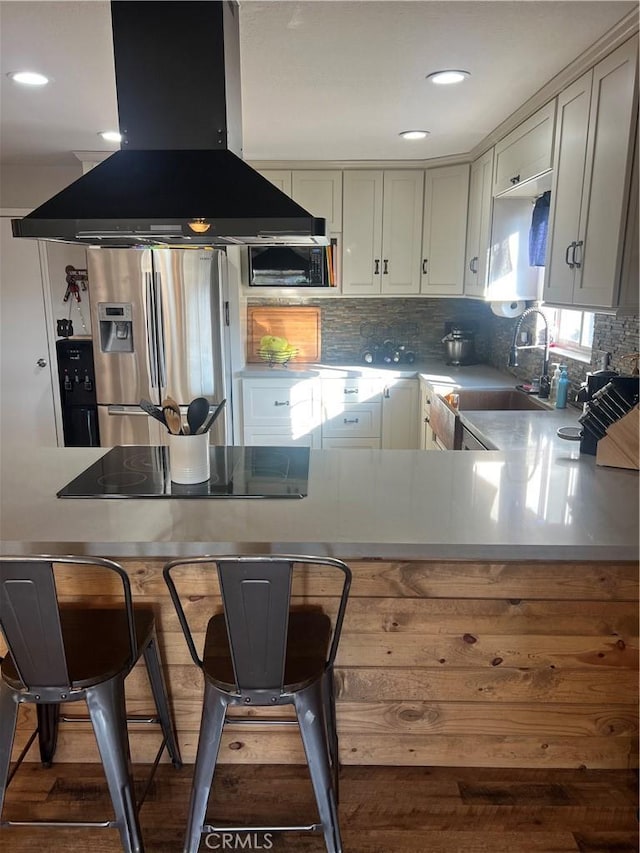 kitchen featuring sink, black appliances, island exhaust hood, dark hardwood / wood-style flooring, and kitchen peninsula