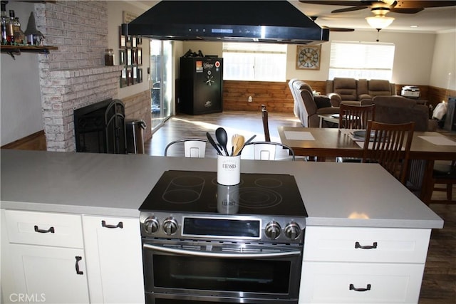 kitchen with white cabinetry, double oven range, a fireplace, and exhaust hood