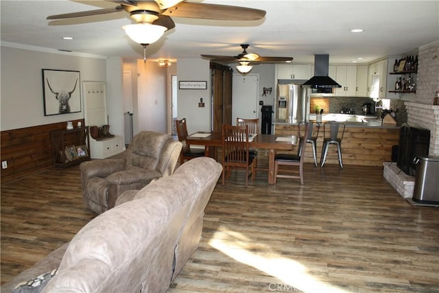 living room featuring a brick fireplace, crown molding, hardwood / wood-style floors, and ceiling fan