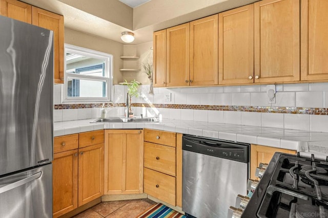 kitchen with sink, light tile patterned floors, appliances with stainless steel finishes, tasteful backsplash, and tile counters