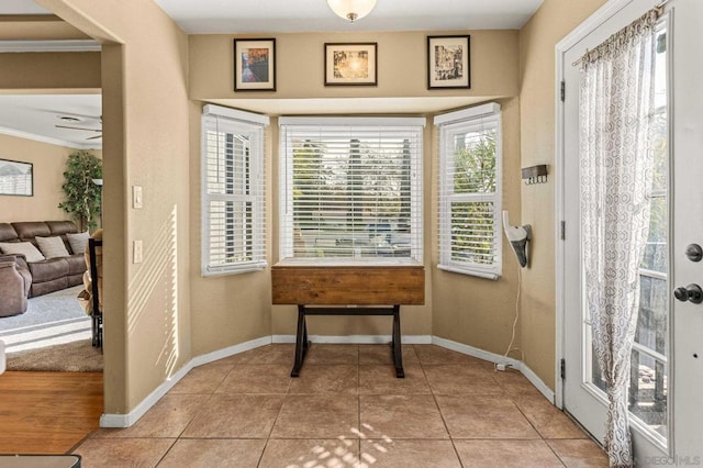 entryway with ornamental molding and light tile patterned flooring