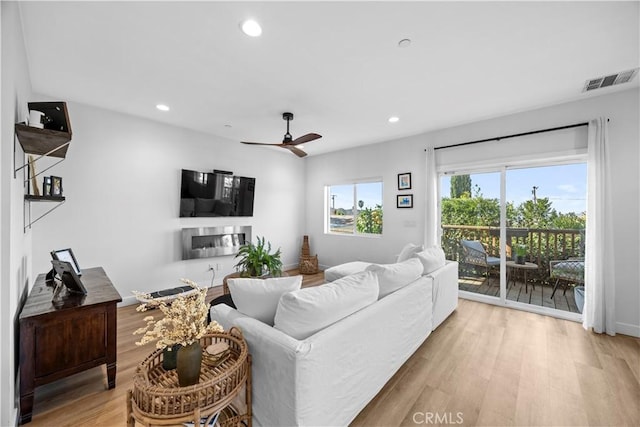 living room with light hardwood / wood-style flooring and ceiling fan