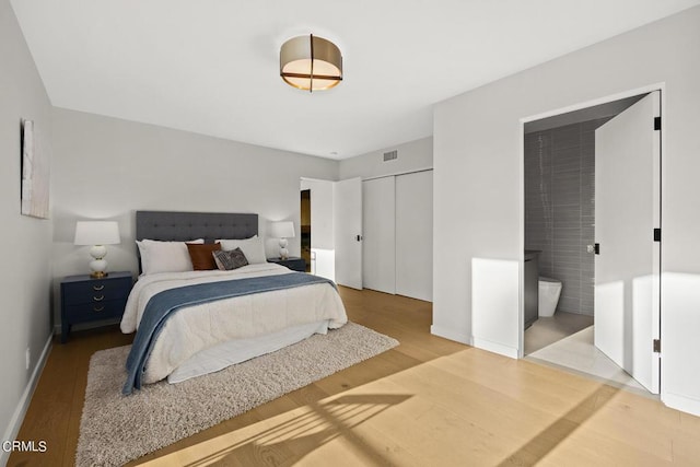 bedroom with ensuite bath, light hardwood / wood-style floors, and a closet