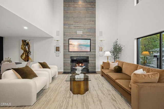 living room featuring a towering ceiling, a fireplace, and light hardwood / wood-style flooring