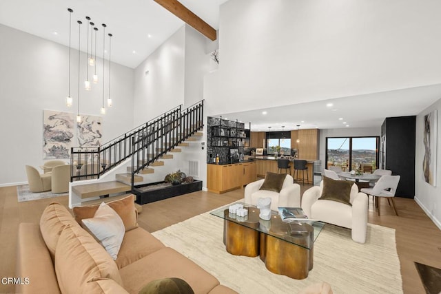 living room featuring beam ceiling, a towering ceiling, and light wood-type flooring