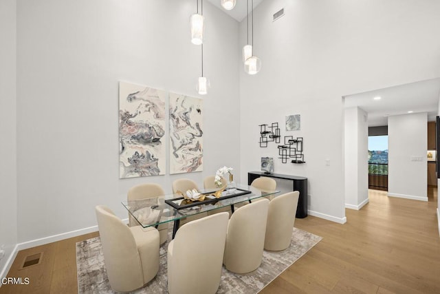 dining area featuring light hardwood / wood-style flooring and a high ceiling