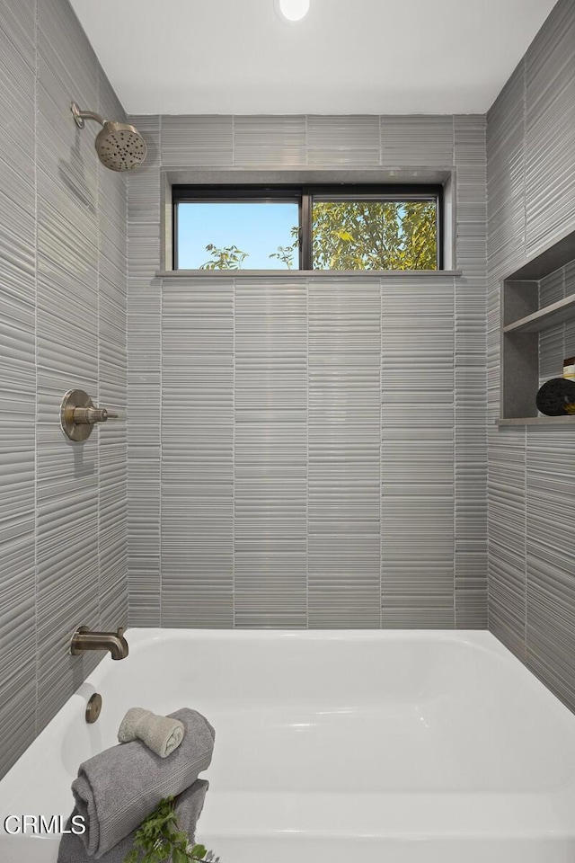 bathroom with tiled shower / bath combo and a wealth of natural light