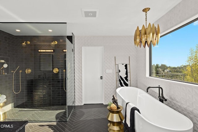 bathroom featuring independent shower and bath, tile walls, and a notable chandelier