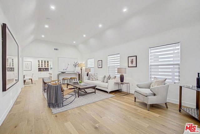 living room with high vaulted ceiling and light hardwood / wood-style floors