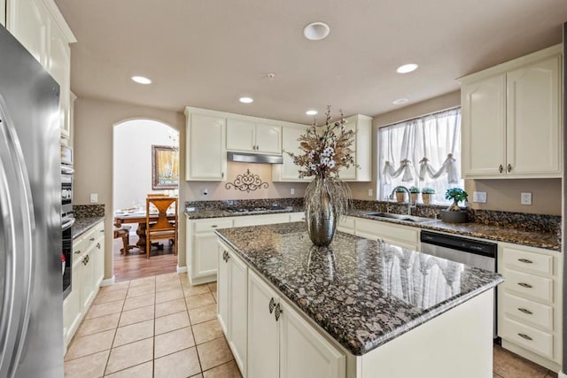 kitchen with light tile patterned flooring, sink, white cabinetry, a center island, and appliances with stainless steel finishes