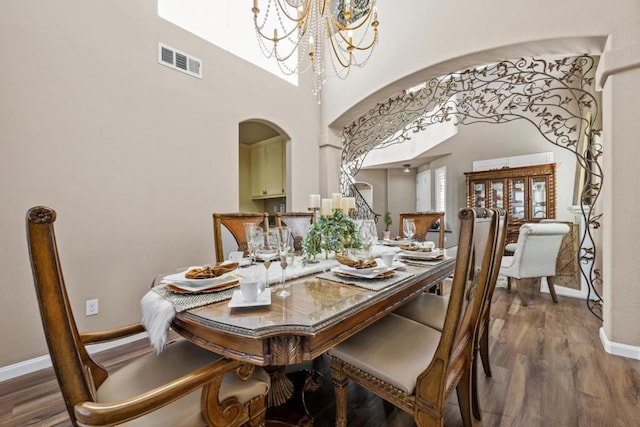 dining room with hardwood / wood-style flooring, a high ceiling, and a chandelier