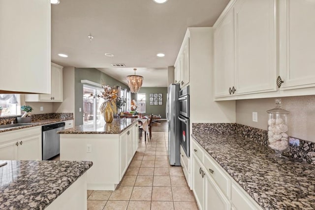 kitchen featuring a kitchen island, appliances with stainless steel finishes, dark stone countertops, and white cabinets