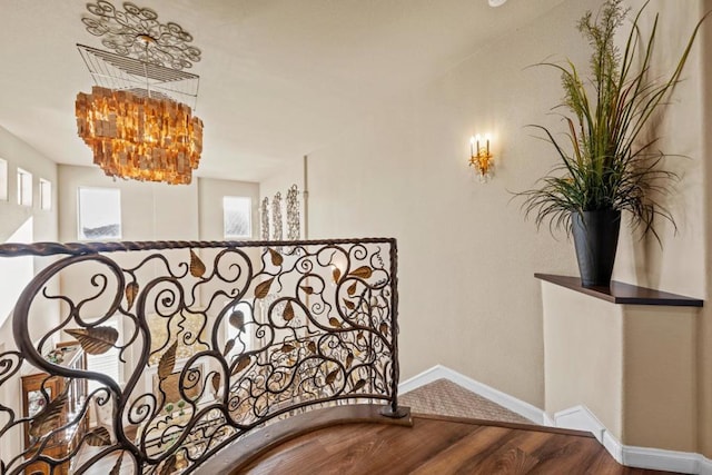 stairway with wood-type flooring and a notable chandelier