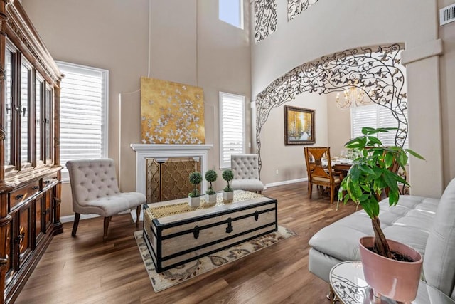 sitting room with a towering ceiling, plenty of natural light, and wood-type flooring