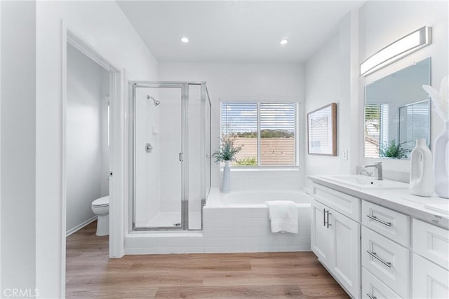 full bathroom with hardwood / wood-style flooring, vanity, independent shower and bath, and toilet