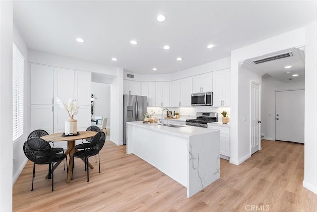 kitchen featuring sink, white cabinetry, a kitchen island with sink, stainless steel appliances, and light hardwood / wood-style floors