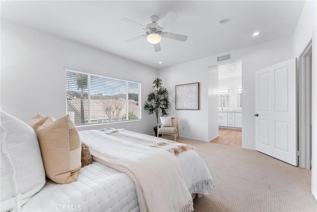 bedroom featuring light carpet, ceiling fan, and ensuite bathroom