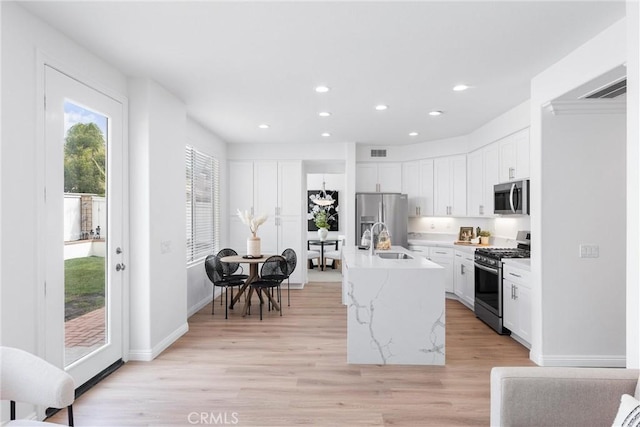 kitchen with a kitchen island with sink, sink, stainless steel appliances, and white cabinets