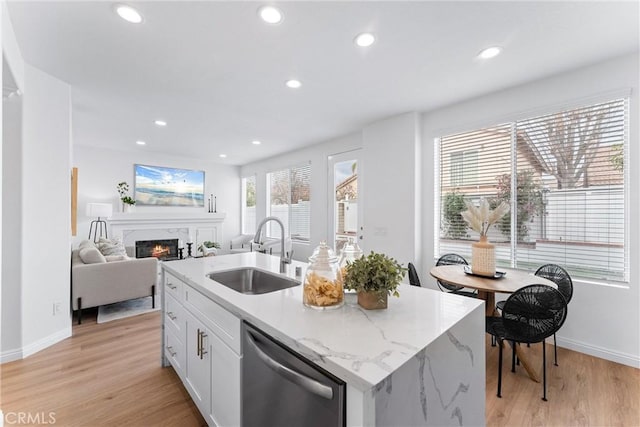 kitchen with sink, white cabinetry, dishwasher, an island with sink, and light stone countertops