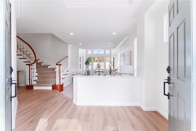 foyer with crown molding and light hardwood / wood-style floors