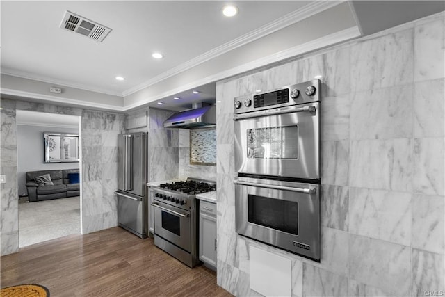 kitchen featuring tile walls, wall chimney range hood, crown molding, dark hardwood / wood-style floors, and premium appliances