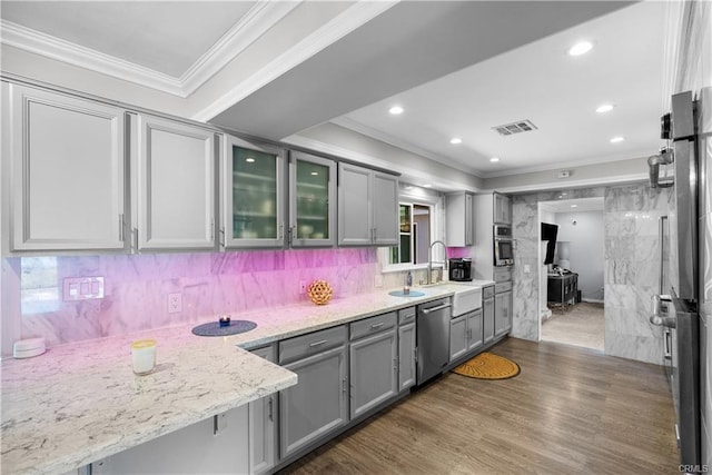 kitchen with appliances with stainless steel finishes, light stone counters, dark hardwood / wood-style floors, crown molding, and decorative backsplash