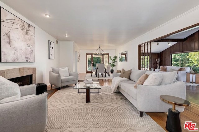 living room with vaulted ceiling, hardwood / wood-style floors, a fireplace, wood walls, and a chandelier