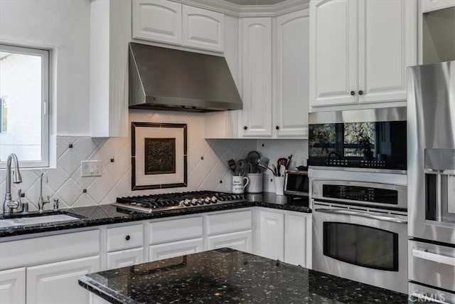 kitchen featuring sink, dark stone counters, stainless steel appliances, decorative backsplash, and white cabinets