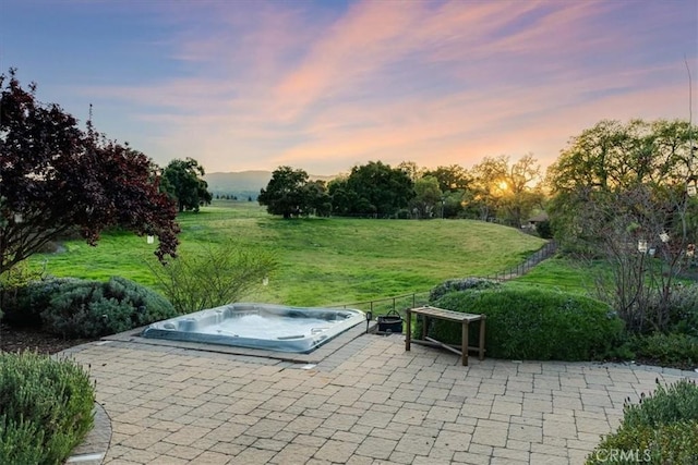 entry to storm shelter featuring a jacuzzi, a patio area, and a lawn