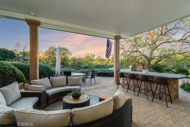 patio terrace at dusk featuring an outdoor hangout area and exterior bar