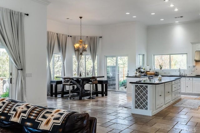 kitchen with a high ceiling, a wealth of natural light, white cabinets, and decorative light fixtures