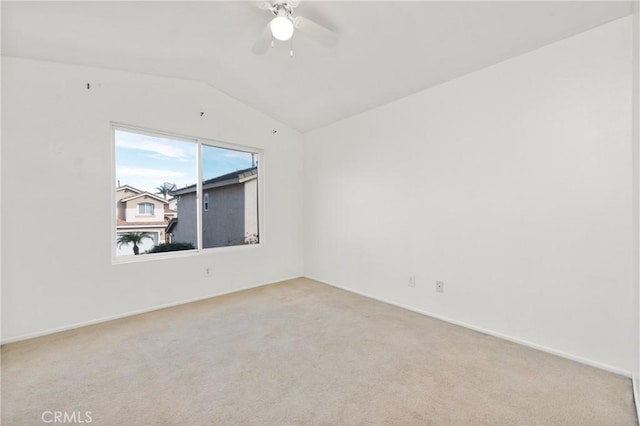 empty room featuring ceiling fan, vaulted ceiling, and light carpet