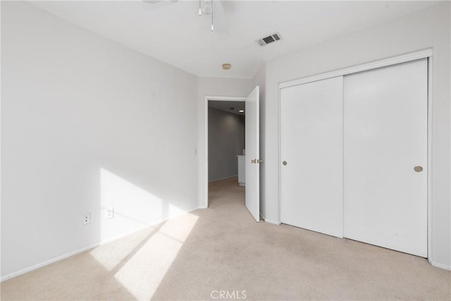 unfurnished bedroom featuring light carpet, ceiling fan, and a closet