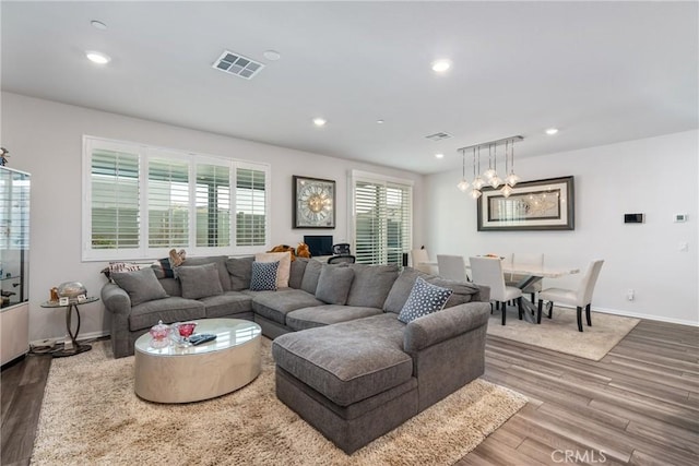 living room featuring wood-type flooring and an inviting chandelier