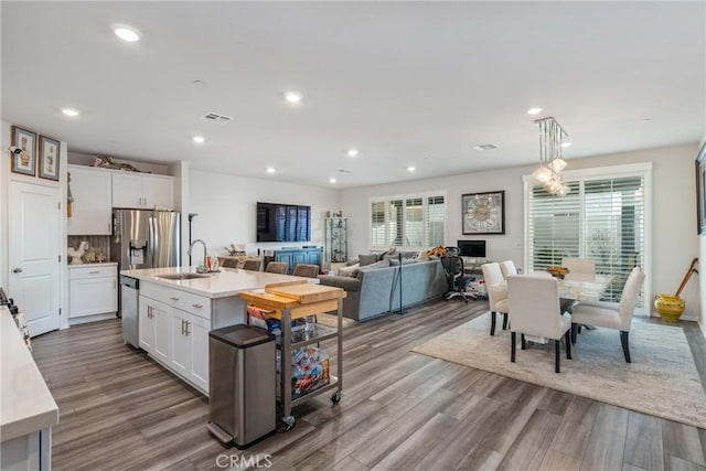 kitchen with white cabinetry, sink, an island with sink, and light wood-type flooring