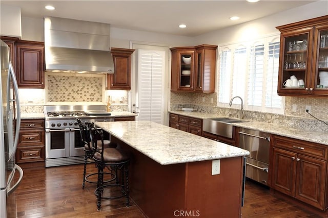 kitchen featuring dark hardwood / wood-style flooring, decorative backsplash, a center island, stainless steel appliances, and wall chimney exhaust hood