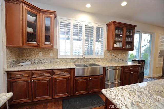 kitchen with tasteful backsplash, sink, dark wood-type flooring, and light stone countertops