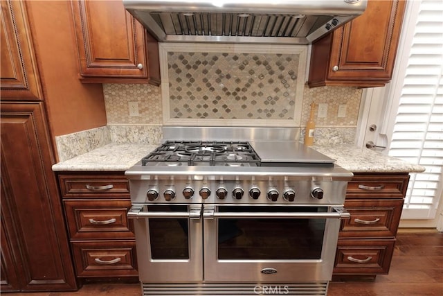 kitchen with extractor fan, light stone countertops, decorative backsplash, and double oven range