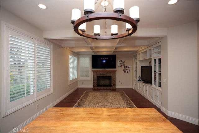 unfurnished living room with beam ceiling, dark hardwood / wood-style floors, coffered ceiling, a notable chandelier, and a brick fireplace